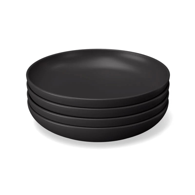 A set of four round plates from the Bamboo Round Plate Set of 4 by Ekobo, crafted from bamboo eco-composite in a matte black finish with smooth edges, is arranged neatly on a white background.