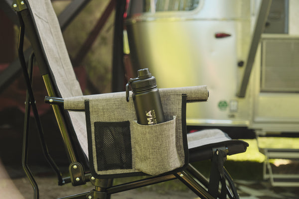 Chair with a cup holder containing a water bottle, set against a blurred background of a vehicle.