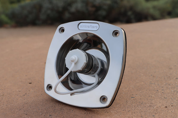 Water inlet on a brown surface with blurred greenery in the background