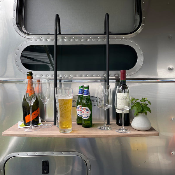 Aluminum wall with a wooden shelf holding bottles and glasses, featuring a retro design.