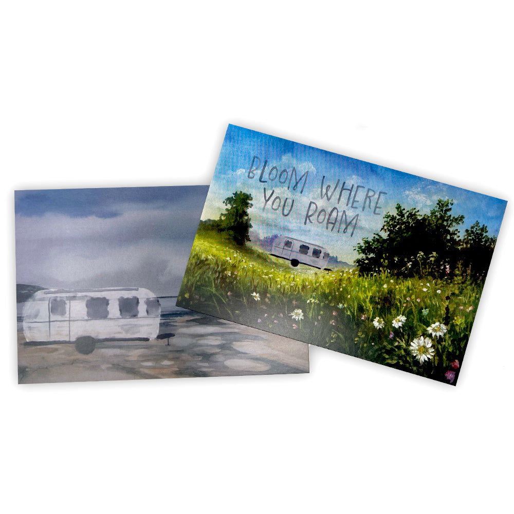 Discover the Airstream Artistic Postcards set: one card depicts a white Airstream trailer in a moody landscape, while the other showcases a trailer in a sunlit field of flowers with the phrase “BLOOM WHERE YOU ROAM.” This artistic postcard duo is perfect for travel enthusiasts.