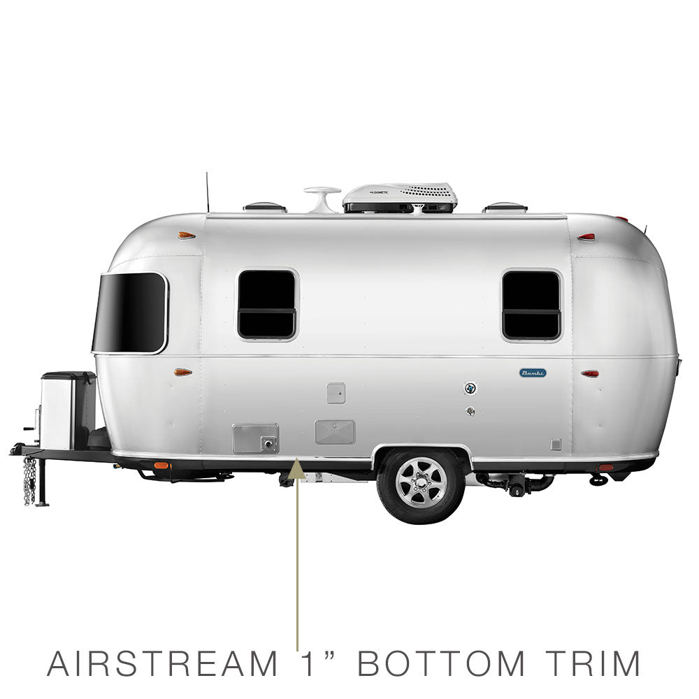 Side view of a silver, riveted aluminum Airstream travel trailer with an arrow pointing to the 1-inch bottom trim. The trailer features two windows and a door, highlighting the location for the Airstream Premium Replacement Rub Rail for Travel Trailers. Text below reads: AIRSTREAM 1 BOTTOM TRIM.