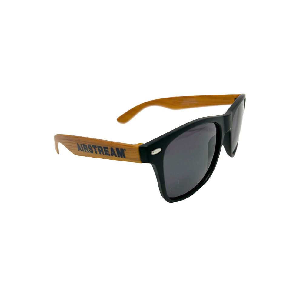 The Airstream Navy Sunglasses are stylish black sunglasses with wooden arms, featuring the AIRSTREAM logo printed on the side and providing excellent sun protection, displayed against a plain white background.