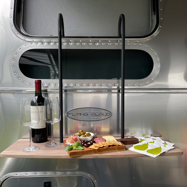 Wine bottle, glasses, and charcuterie board on a wooden tray with 'Flying Cloud' branding in the background.