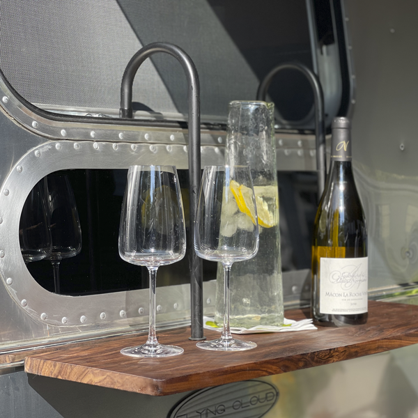 Wine glasses and a bottle on a wooden shelf with a metallic background