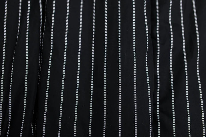 The Bryant Luxe Blanket by Beddy’s features black fabric with evenly spaced vertical white dashed stripes, creating a sleek, contemporary look—perfect for adding modern style to your space.