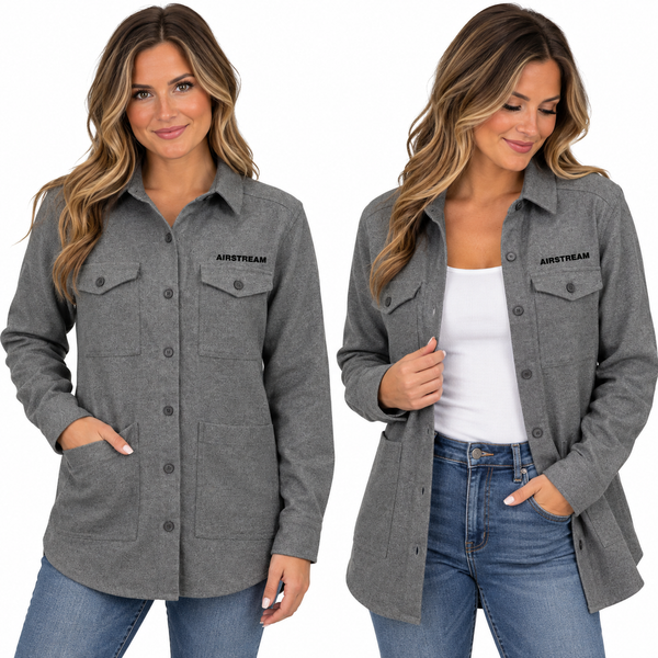 Two women wear the Airstream Women’s Long Sleeve Twill Overshirt in gray, featuring chest pockets. One has her shirt buttoned, while the other styles hers open over a white top. Both are smiling with their hands in their pockets and wear blue jeans.