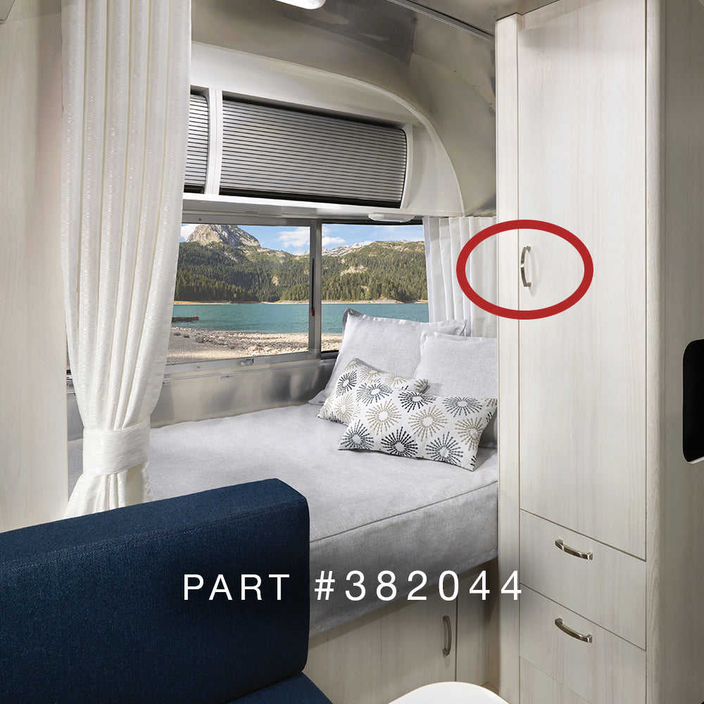 Interior of an RV with a made bed, patterned pillows, white cabinetry, and a mountain lake view through the window. A red circle highlights the Airstream Interior Pull Handle | Part # 382044 Series. Text reads: PART #382044.