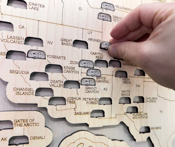 Hand interacting with a wooden map of national parks
