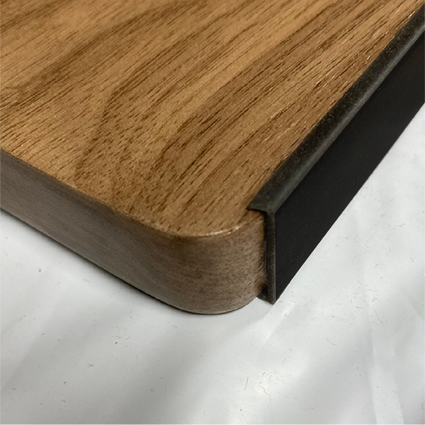 Close-up of a wooden cutting board with a black edge on a white surface
