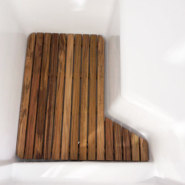 The Airstream Teak Shower Mat for World Traveler Travel Trailers, with its rectangular shape and evenly spaced slats, is placed inside a white bathtub, fitting snugly against the tub’s angled edge.