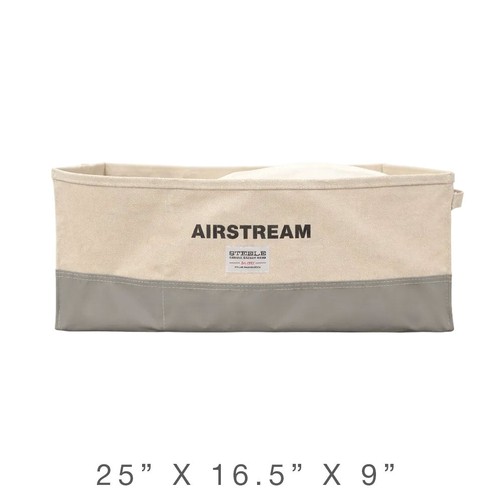 The Airstream x Steele Canvas Custom Storage Bin is a rectangular beige and gray storage solution labeled “AIRSTREAM” on the front, measuring 25 x 16.5 x 9 inches—a stylish custom bin perfect for organizing your travel trailer.