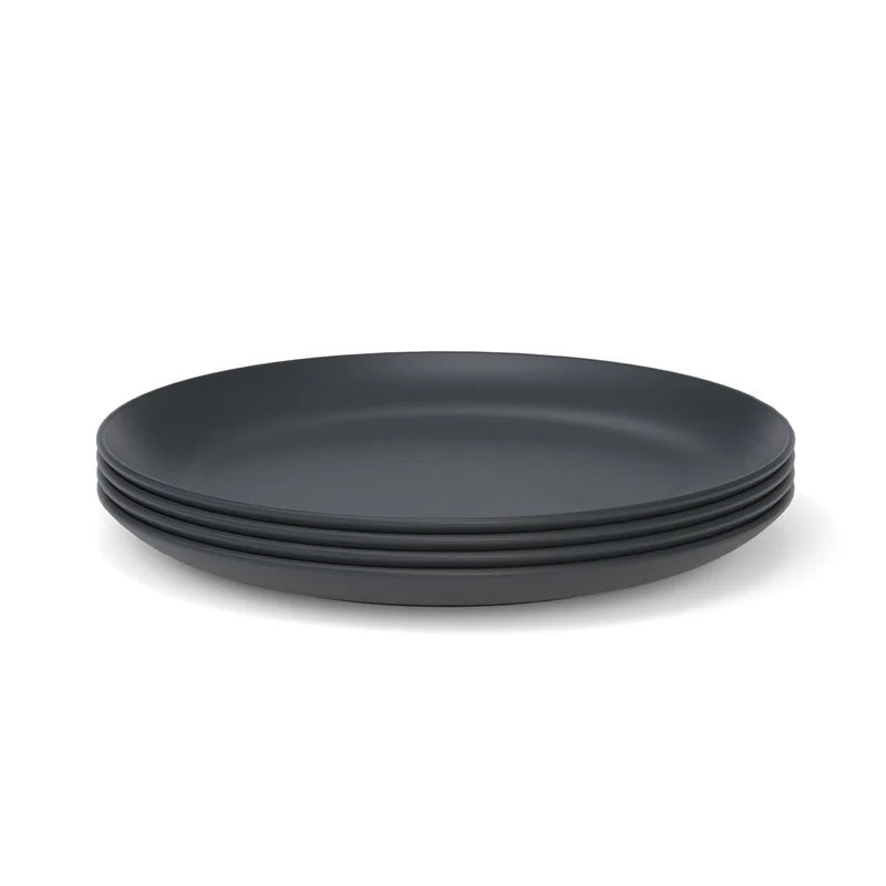 A set of four matte black Bamboo Round Plates by Ekobo, crafted from bamboo eco-composite, is displayed against a white background.