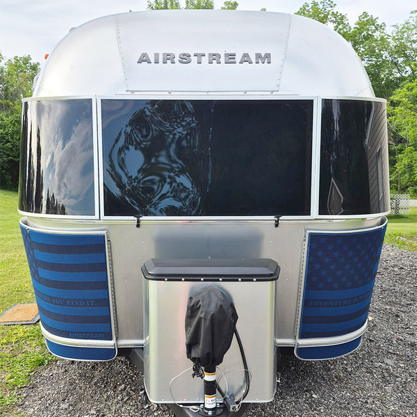Airstream travel trailer with blue and white exterior in a natural setting