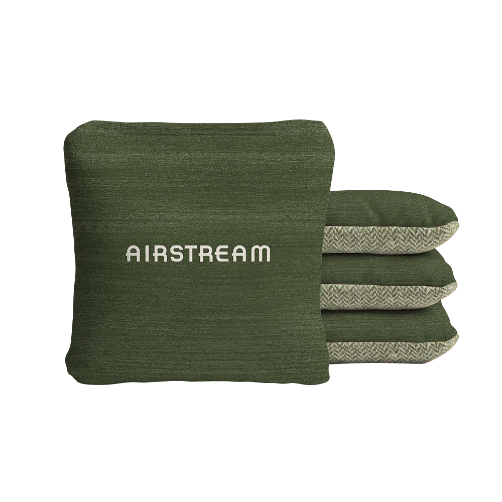 Four green Airstream ACA Cornhole Bags are stacked, with the front bag displaying the word “AIRSTREAM” in white text. The edges feature a subtle herringbone pattern, reminiscent of high-quality custom cornhole bags for a polished touch.
