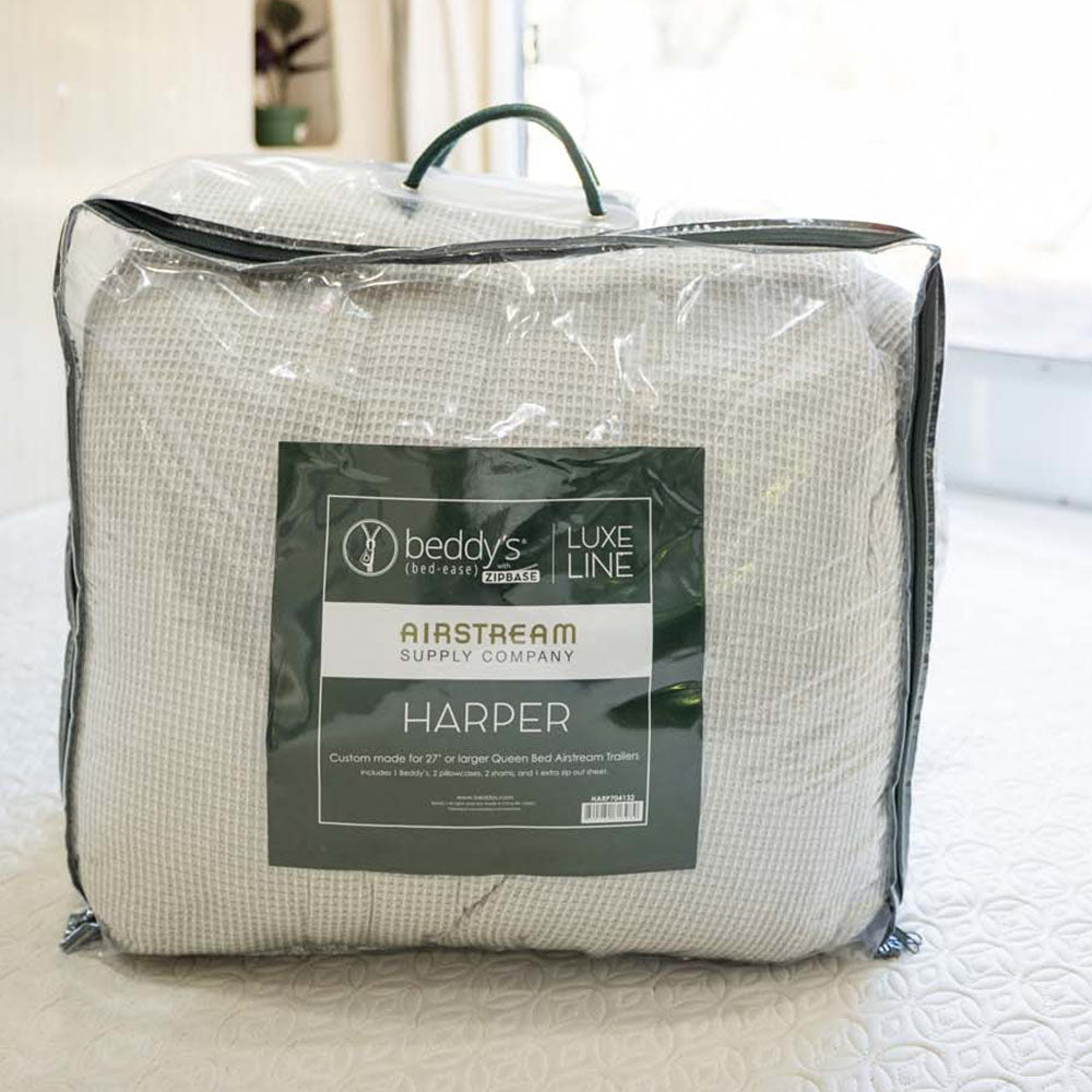 A packaged Airstream Custom Fit Beddy’s for Bambi Travel Trailers bedding set, designed specifically for 72 x 80 Airstream queen beds, sits on a bed in a bright room—perfect for those seeking stylish and convenient zippered bedding tailored for Airstream enthusiasts.