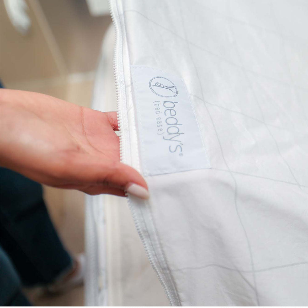 A hand zipping up the Airstream Custom Fit Beddy’s for Caravel Travel Trailers, with the branded label visible near the zipper—highlighting this convenient all-in-one bedding solution, ideal for any bed and perfectly tailored for Airstream Caravel travel trailers.