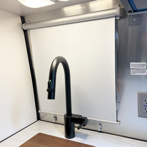 The white window shade pulled down in an Airstream Caravel Travel Trailer kitchen