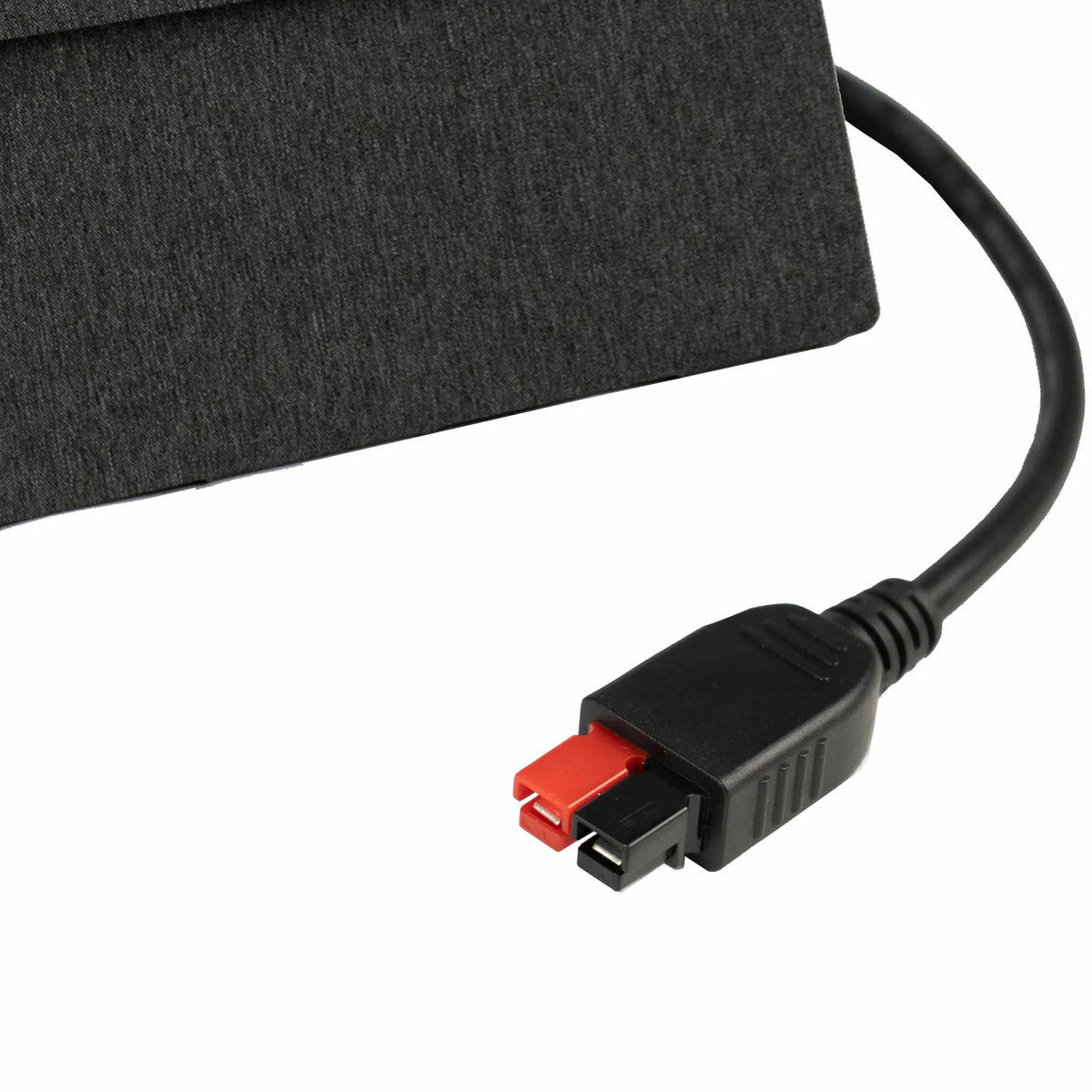 A close-up of a black and red rectangular power connector attached to a black cable, placed on a dark textured surface—ideal for connecting the High Efficiency Folding Solar Panel by Wagan Tech and harnessing outdoor solar power.
