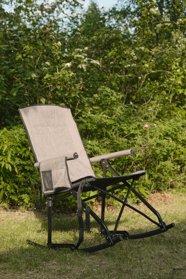 Foldable rocking chair on grass with greenery in the background