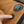 Close-up of a person's finger pressing a black power switch on a tan and black camping chair, with a circular embroidered logo patch visible on the fabric.