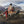 Person sitting on a camping chair with a dog, surrounded by mountains and nature.