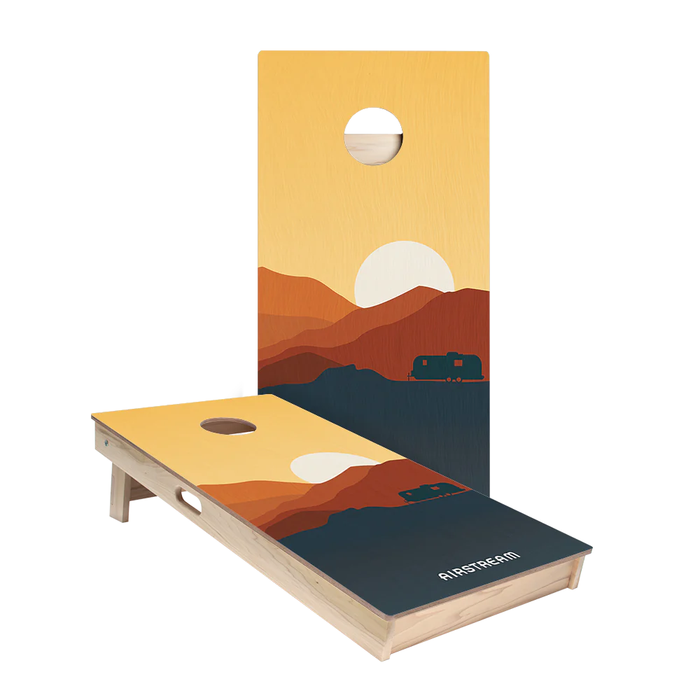 Experience classic outdoor fun with the Airstream ACA 2 x 4 Star Cornhole Boards—featuring two regulation-size boards adorned with a sunset mountain landscape and an iconic Airstream trailer graphic. One board stands upright while the other rests flat, proudly displaying “AIRSTREAM” in bold white letters. Officially inspired by the American Cornhole Association, these boards infuse your next game with adventurous style.
