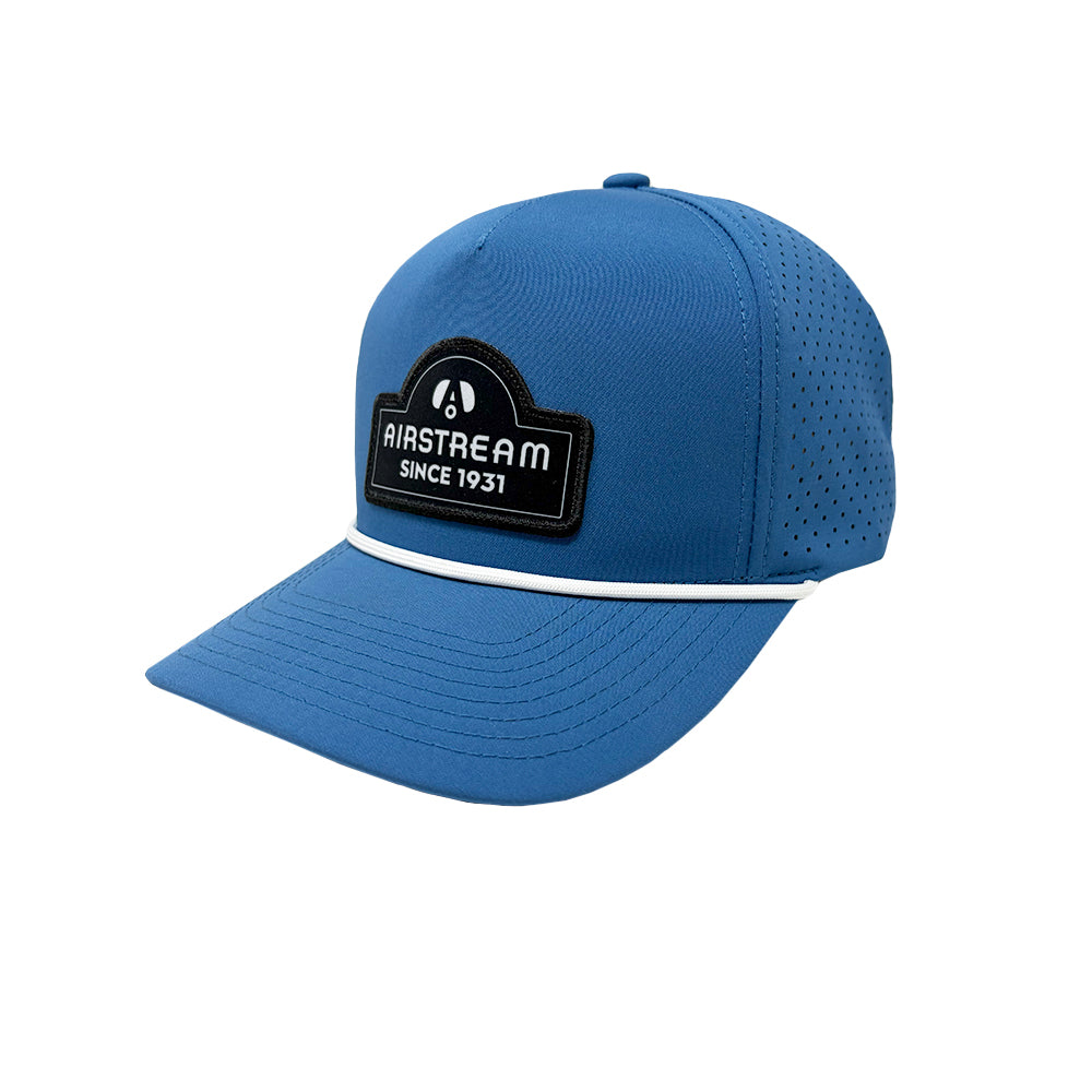 The Airstream 1931 Series Hat is a blue baseball cap featuring a black and white “Airstream Since 1931” patch on the front and small ventilation holes on the sides. A thin white line borders the edge of the visor, making it a stylish addition to your travel trailer accessories collection.
