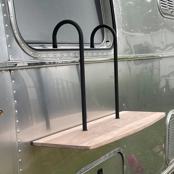 Wooden shelf with metal brackets attached to the side of a metallic vehicle