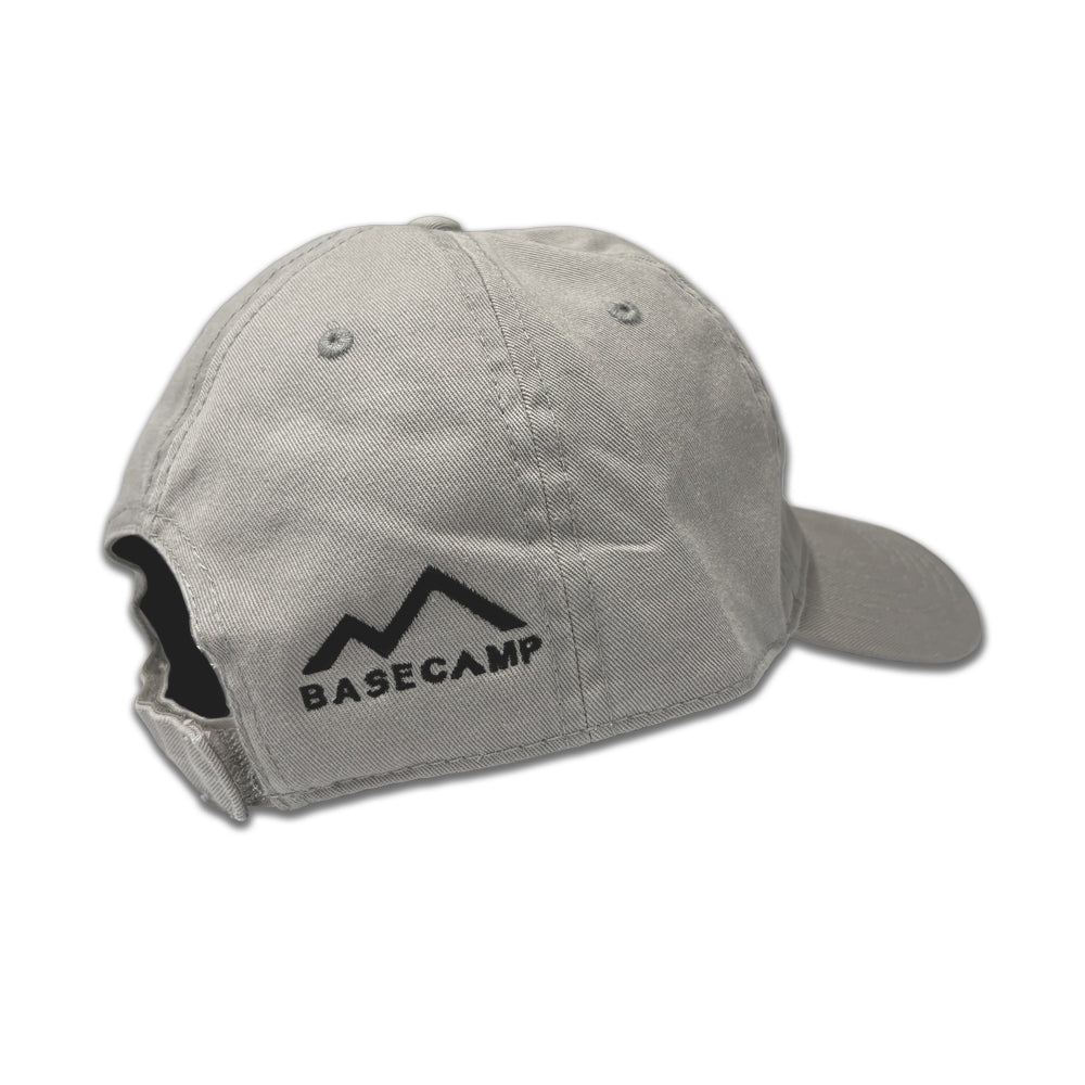 A light gray Airstream Basecamp Outline Hat featuring “BASECAMP” and a mountain logo printed in black on the back. Designed for outdoor adventures, it offers an adjustable strap and two ventilation eyelets—making it ideal for every Airstream Basecamp journey.