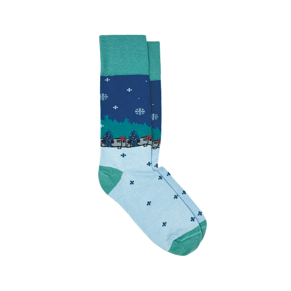 Airstream Christmas Socks with a winter theme in blue and teal, decorated with snowflakes, green trees, and small houses. These socks feature a teal cuff, heel, and toe, with a lighter blue foot adorned in small blue dots—perfect for cozy evenings or as travel trailer socks on your next adventure.