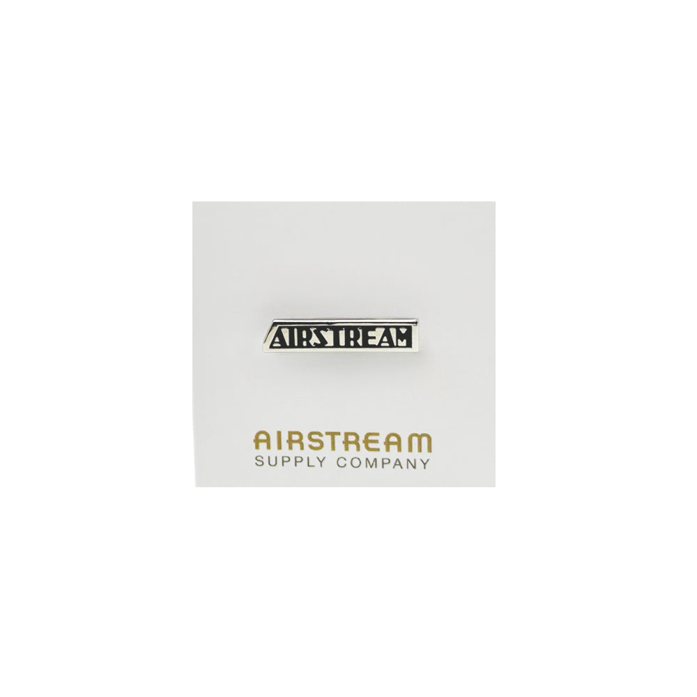 Introducing the Airstream Heritage Logo Pin—a small metallic enamel accessory showcasing the bold black Airstream logo. Presented on a white card with “AIRSTREAM SUPPLY COMPANY” elegantly printed in gold at the bottom, this classic retro pin is a must-have for any true enthusiast.