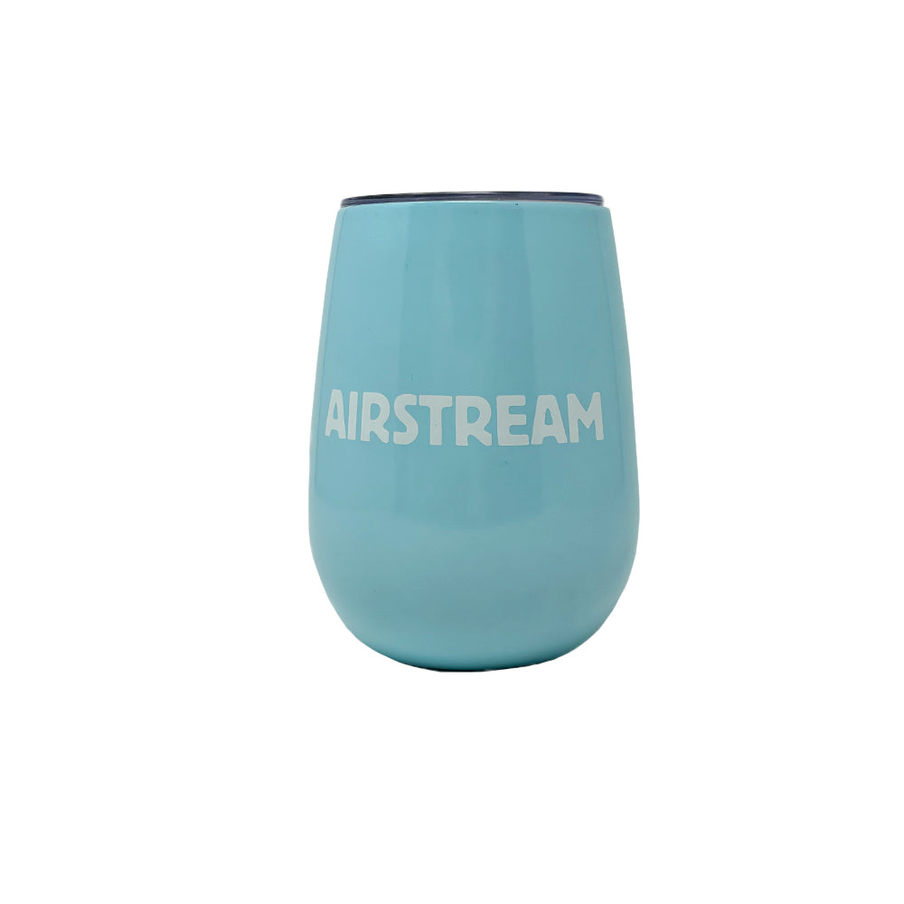 The Airstream Let’s Go Explore Wine Tumbler is a light blue insulated wine tumbler featuring the word “AIRSTREAM” printed in bold white capital letters on the front. It stands upright against a plain white background.