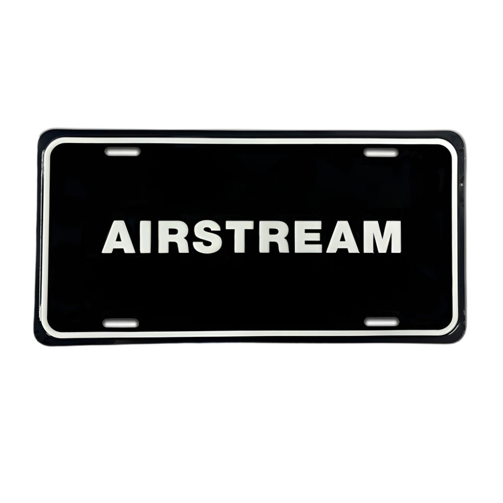 The Airstream Aluminum License Plate is a sleek black accessory crafted from durable aluminum, featuring the word “AIRSTREAM” in bold white capital letters at its center. Designed with four mounting slots near the edges, this stylish plate is perfect for adding a distinctive Airstream touch to your travel trailer or tow vehicle.