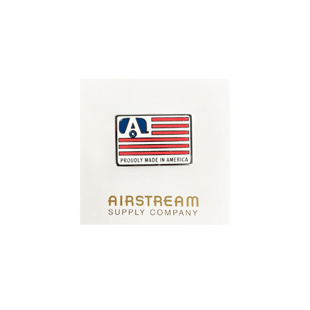 The Airstream Made in America Flag Pin is a rectangular pin featuring red stripes, a blue Airstream logo, and the words “Proudly Made in America.” Beneath this, “Airstream Supply Company” is displayed on a white background.