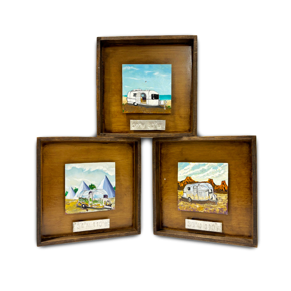 Set of three Airstream Original Painting in Shadow Box Frame pieces, each featuring a unique hand-painted scene with a camper or trailer: one by the beach, one with tents, and one in a desert landscape. Crafted as distinctive salvaged Airstream trailer art and adorned with charming Airstream painting details, these wooden shadow boxes are ideal as Americana wall decor. Each frame is finished with a metal label at the bottom.