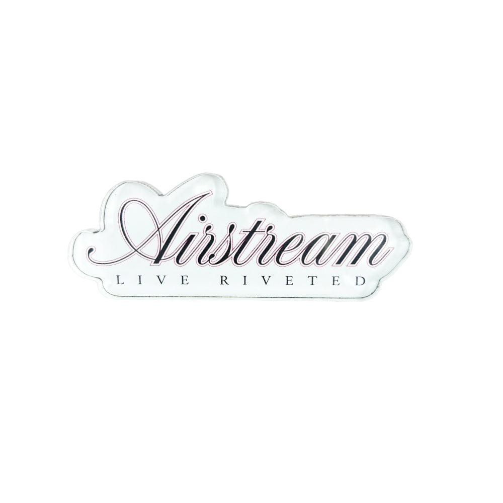 Introducing the Airstream Signature Series Acrylic Magnet—a white sticker featuring “Airstream” in elegant script above bold, uppercase “LIVE RIVETED” lettering, capturing the iconic look of classic Airstream collectibles for your fridge or collection.