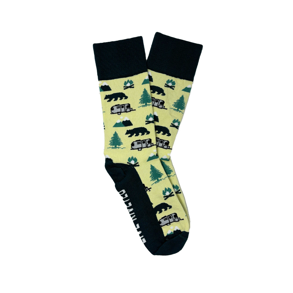 Airstream Trailer Mountain Socks: Cozy yellow cabin socks with black toes, heels, and cuffs, featuring a repeating pattern of black bears, green trees, and gray campers. The sole displays white text on a black background—perfect for fans of cozy mountain-themed or Airstream Trailer Socks styles.