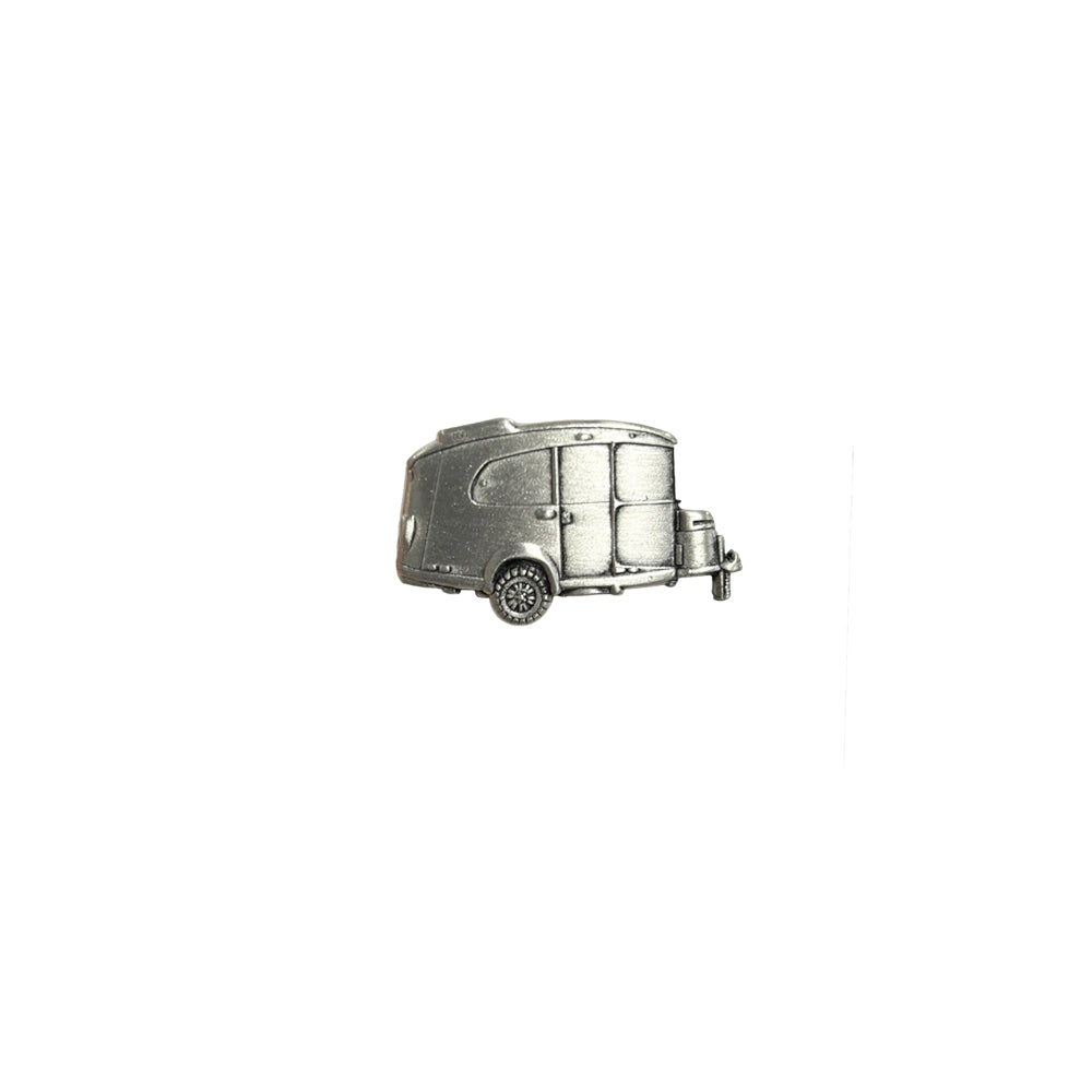 A small, silver Airstream Basecamp Pin designed in a vintage style, featuring a rounded shape and two wheels, is displayed against a plain white background.