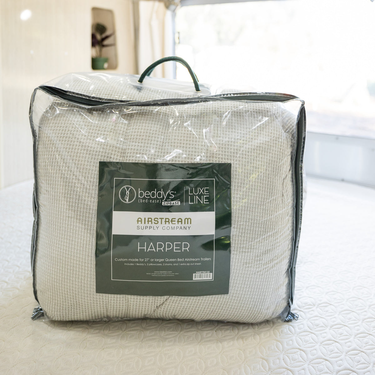 A packaged Airstream Custom Fit Beddy’s for Flying Cloud Travel Trailers all-in-one bedding set sits on a bed inside a bright, modern trailer bedroom, showcasing the convenience and style of zippered bedding designed specifically to fit Airstream travel trailers.