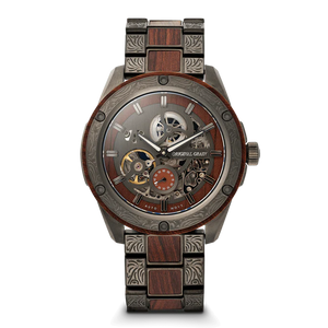 A luxury skeleton wristwatch with a dark wood and gunmetal steel link bracelet, featuring a detailed open-heart dial with visible gears and a small orange sub-dial. The brand name 'OAKRIVL GRAND' is printed on the dial.
