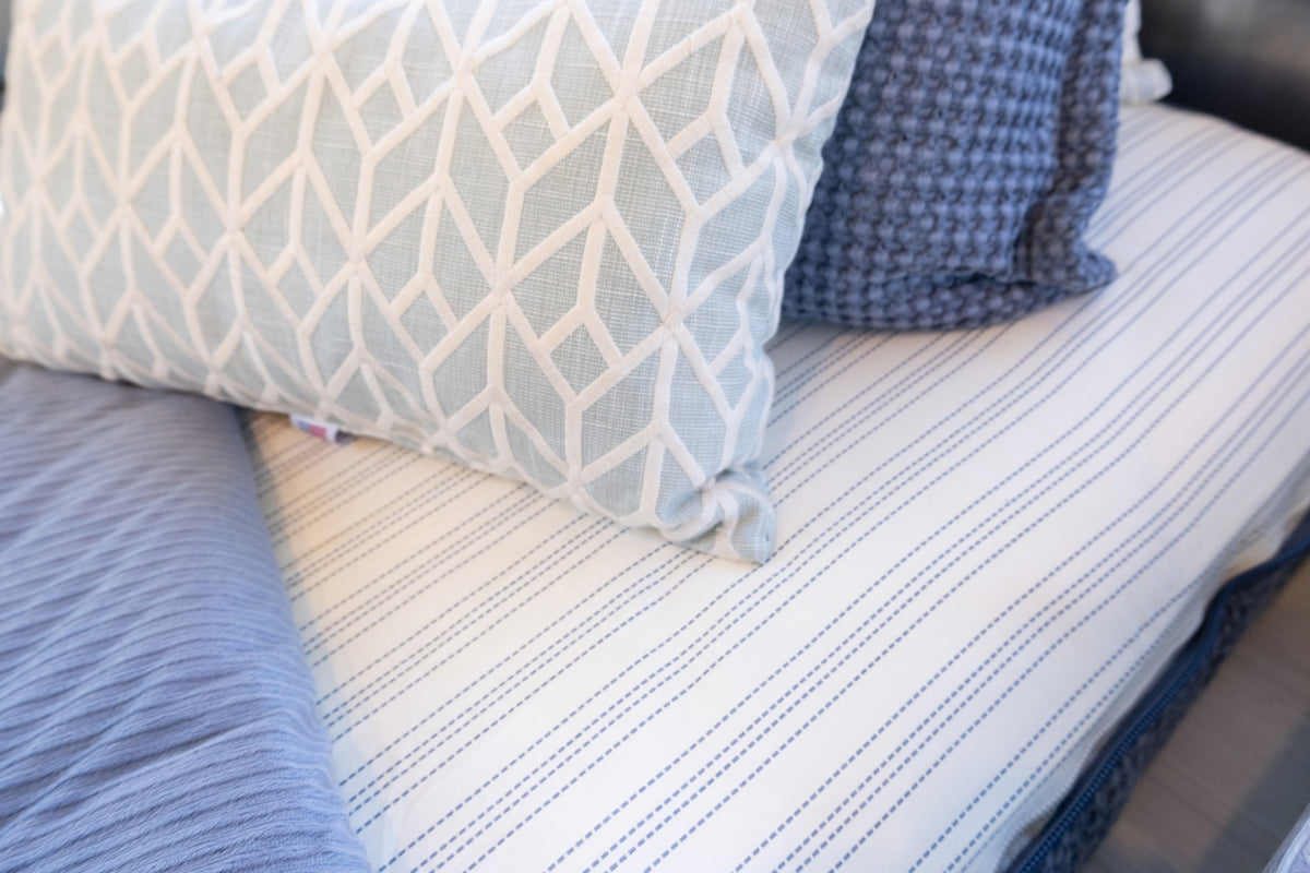 Airstream Custom Fit Dual Comfort Beddy’s for Globetrotter Travel Trailers featuring blue-and-white striped bedding, a light blue pillow with a white geometric pattern, and a dark blue textured pillow.