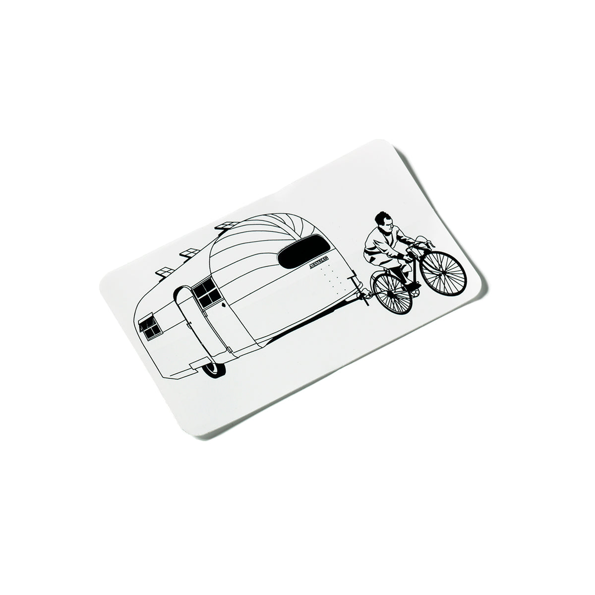 A black-and-white drawing of a person riding a bicycle and towing a large, vintage-style camper trailer—decorated with Airstream Heritage Center Stickers—behind them, on a white rectangular surface.