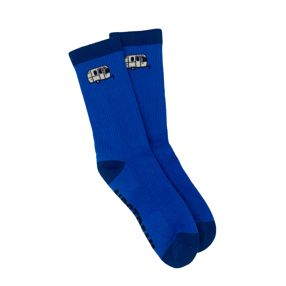 Introducing the Airstream Travel Trailer Athletic Socks: a pair of vibrant blue crew socks featuring a small white Airstream travel trailer design near the top—ideal for anyone with a spirit of adventure. The toes and heels are accented in a darker blue, while the soles showcase black text or patterns.