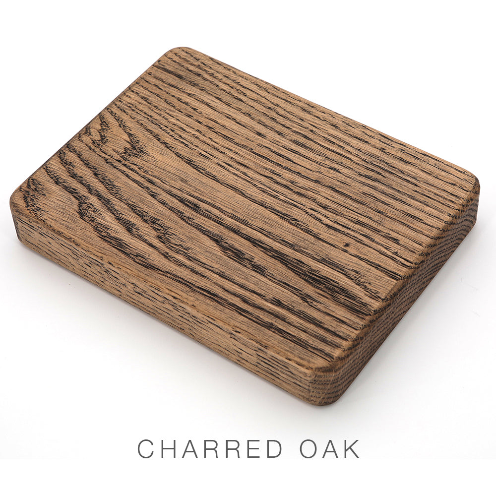 Airstream Wood Rear Dinette Table Upgrade for Basecamp Travel Trailers—a rectangular wooden board featuring dark, charred grain patterns on its surface that evoke the refined craftsmanship of a premium dinette table. The text CHARRED OAK appears below the board.
