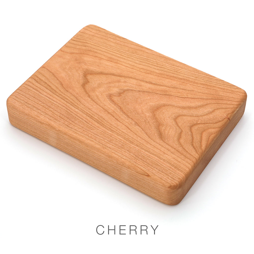 A rectangular cherry wood block with rounded edges on a white background evokes the elegant craftsmanship of the Airstream Wood Dinette Table Upgrade for Pan America Travel Trailers. The word CHERRY is written below the block.