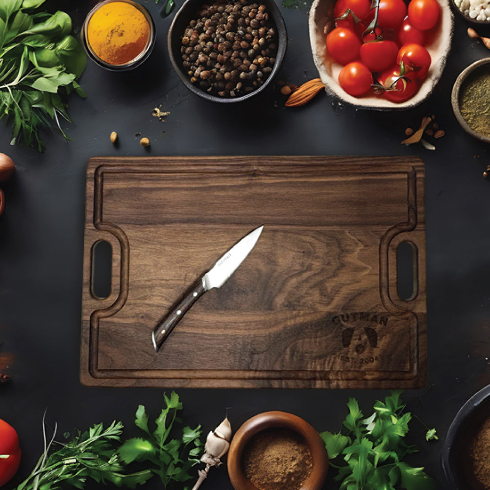An Airstream Personalized Cutting and Serving Board with a knife rests on a table, surrounded by fresh herbs, cherry tomatoes, spices, and bowls of seasonings, ready for meal preparation.