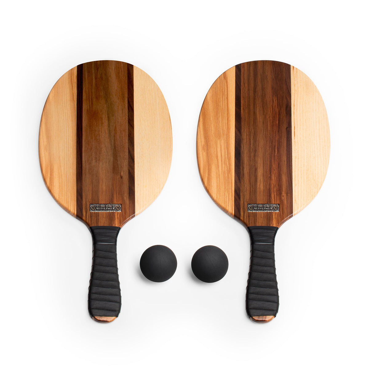 The Paddle Ball Set features two wooden paddles with black handles, placed side by side on a white background. Two black balls are positioned below each handle, making this set perfect for your next beach game.