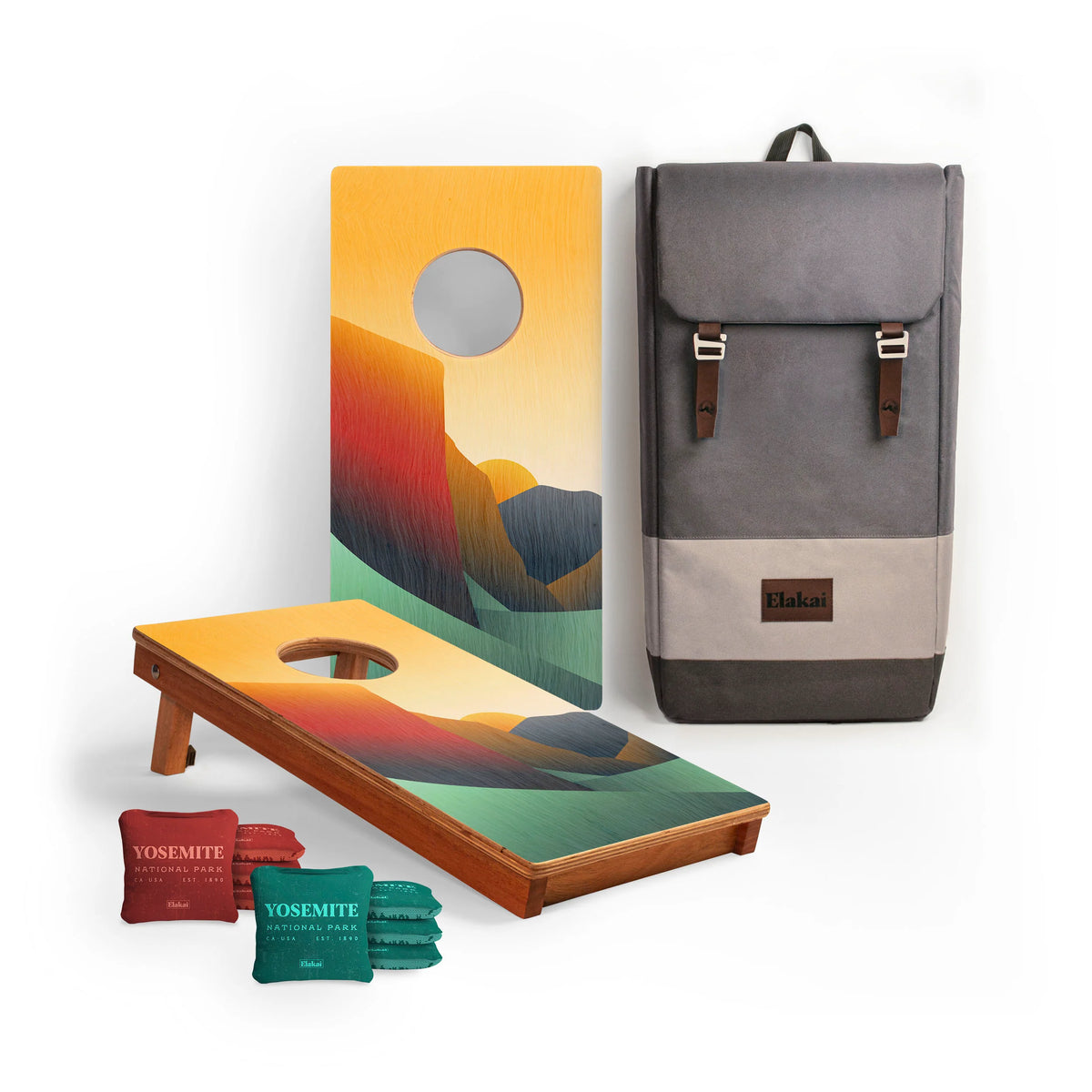 The National Parks Travel Size Cornhole Boards by Elakai are shown on a white background, featuring a vibrant Yosemite-inspired design, bean bags labeled “YOSEMITE,” and a stylish two-tone gray backpack with leather accents—an ideal choice for National Park cornhole board enthusiasts.