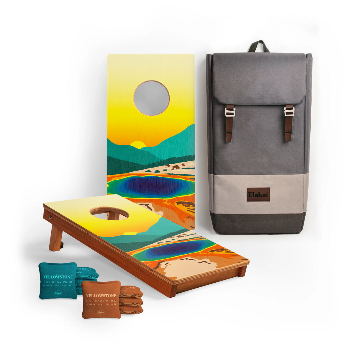 A vibrant National Parks Travel Size Cornhole Boards set by Elakai, showcasing colorful Yellowstone-themed artwork, includes matching bean bags and a gray backpack with leather accents—all travel-sized cornhole essentials displayed on a white background.